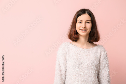 Teenage girl with dental braces on color background