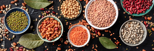 Legumes flat lay panorama, shot from the above on a black background. Lentils, soybeans, chickpeas, red kidney beans, a vatiety of pulses photo