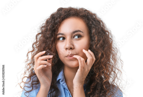 Young African-American woman with chocolate on white background