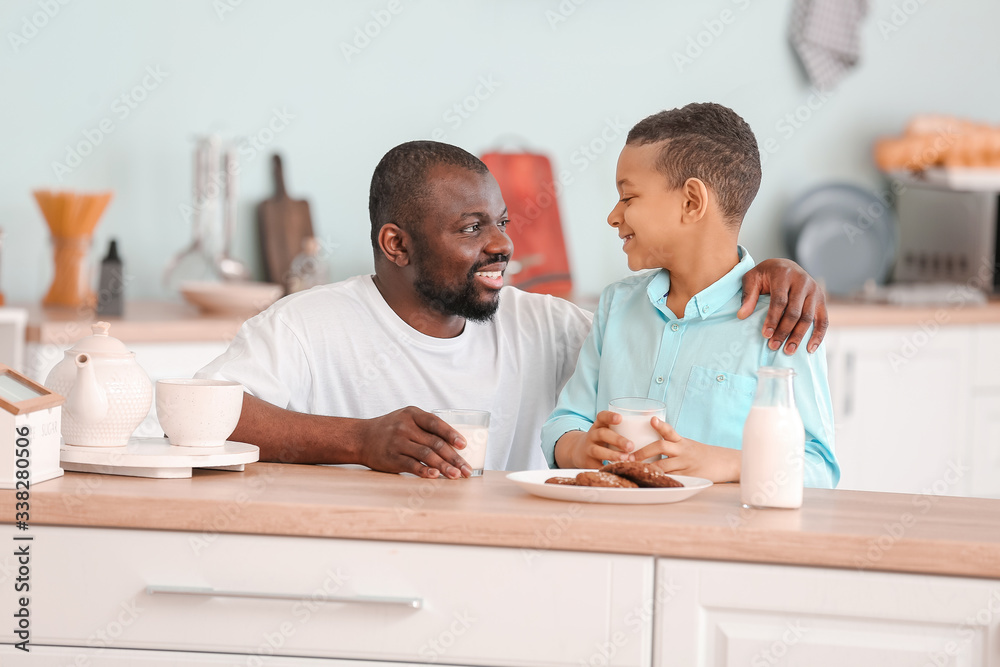 Obraz premium African-American boy and his father drinking milk in kitchen