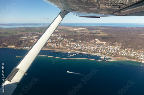 View from a single-engine small aircraft on the German Baltic island of Rügen and the port city of Sassnitz. The port with buildings and ships is clearly visible. Cape Arkona is on the horizon.