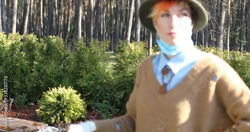 A stylish woman wearing mask and gloves to defened her from coronavirus. Using electric scooter in city and park to be in safe.