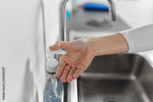 hygiene, health care and safety concept - close up of female woman washing hands with liquid soap in kitchen at home