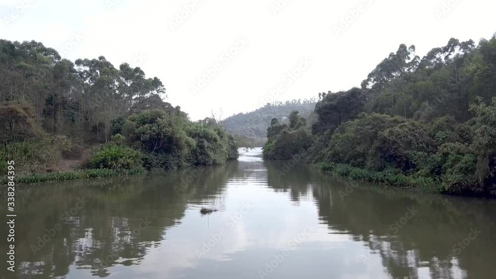 Slow fly over River going to resevoir, surrounded by tree foliage Slow fly over River going to resevoir, surrounded by tree foliage