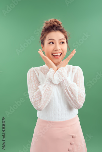 Image of excited young girl standing isolated over green background make lovely gesture