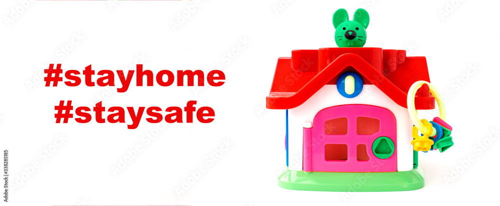 Toy house with keys and mouse inside.Сoncept of preventing the spread of a coronavirus pandemic.Words #stayhome #staysafe on a white background