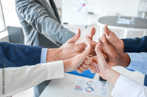 Group of business people putting hands together in office. Unity concept