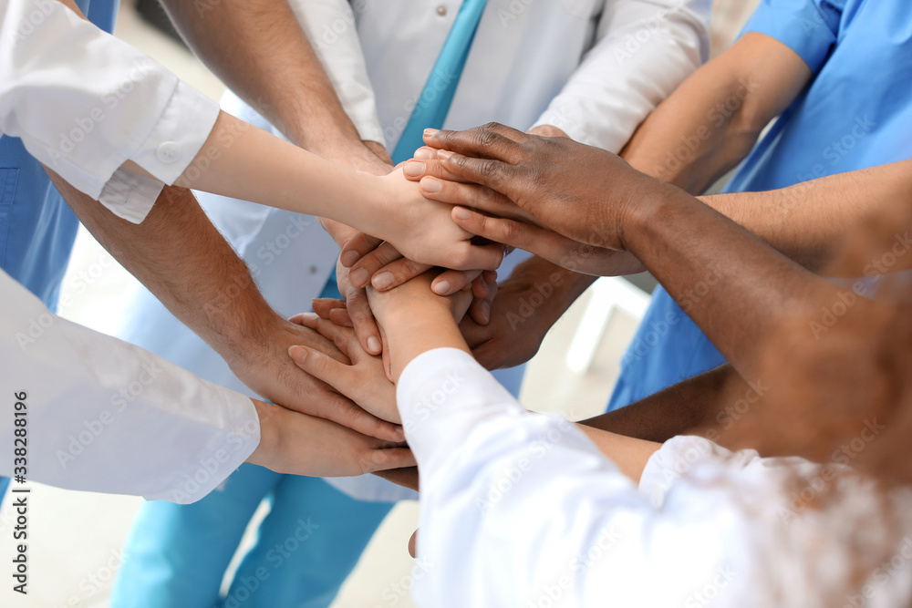 Group of doctors putting hands together in clinic. Unity concept Group of doctors putting hands together in clinic. Unity concept