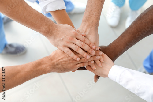 Group of doctors putting hands together in clinic. Unity concept