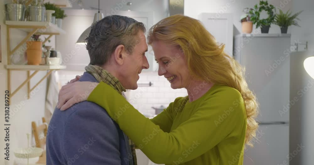 Senior lovely husband and wife hugging in kitchen Senior lovely husband and wife hugging in kitchen