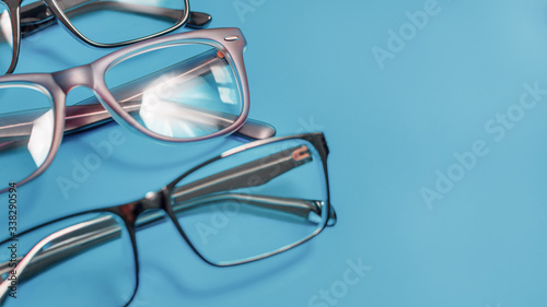 Blue background with three corrective medical eyeglasses and a reflection in the glass lens