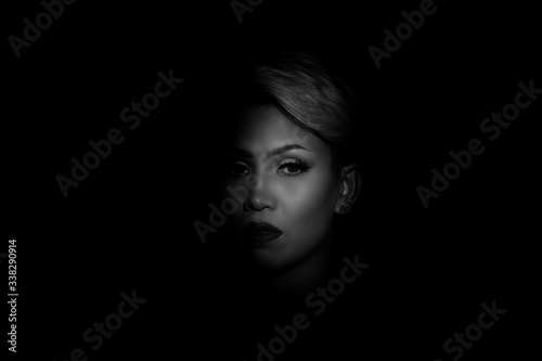 Portait photography of the face of a young asian woman with black background. Spot light portrait. Expressive girl portrait on dark background. Girl with a spot of light on her face. Sad face.