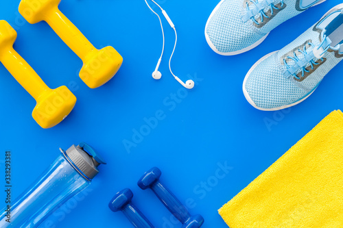 Fototapeta Naklejka Na Ścianę i Meble -  Sport flat-lay with dumbbells, towel, headphones on blue background top-down