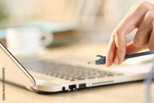 Woman hands plugging ethernet cable on laptop