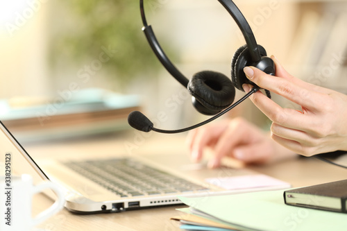 Telemarketer holding headset working on laptop photo