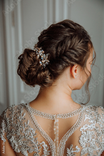 Bride's hairstyle. Beautiful decoration in the hairstyle. The wedding dress is embroidered with beads