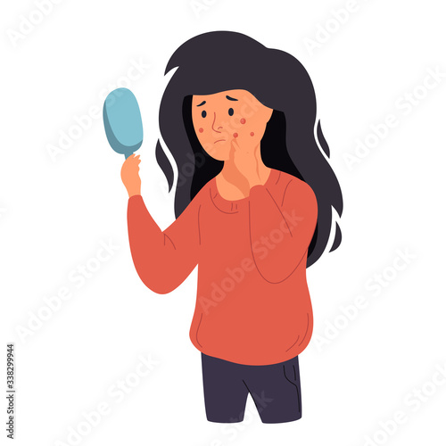 A woman examines her face in a mirror. Acne, skin problems and acne.