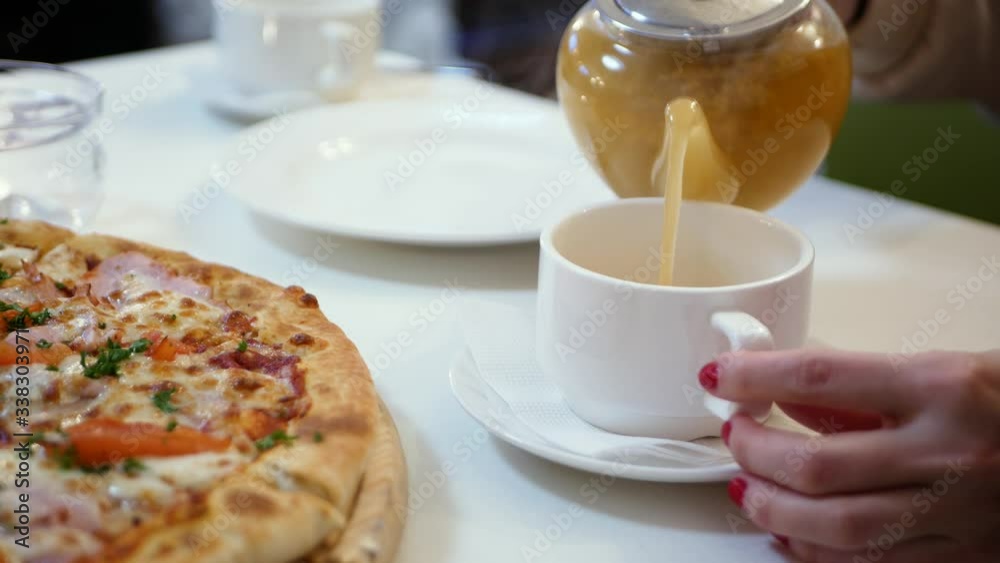 girl pours sea-buckthorn tea from a teapot. close-up. Woman in cafe pours from french press sea-buckthorn tea in cups, hands closeup. girl pours sea-buckthorn tea from a teapot. close-up. Woman in cafe pours from french press sea-buckthorn tea in cups, hands closeup.