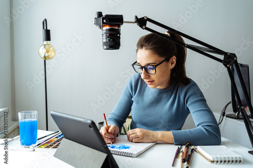 Online content creator vlogger. A young women blogger with glasses removes the content for the blog, training courses. The concept of online learning to draw on walercolor. photo