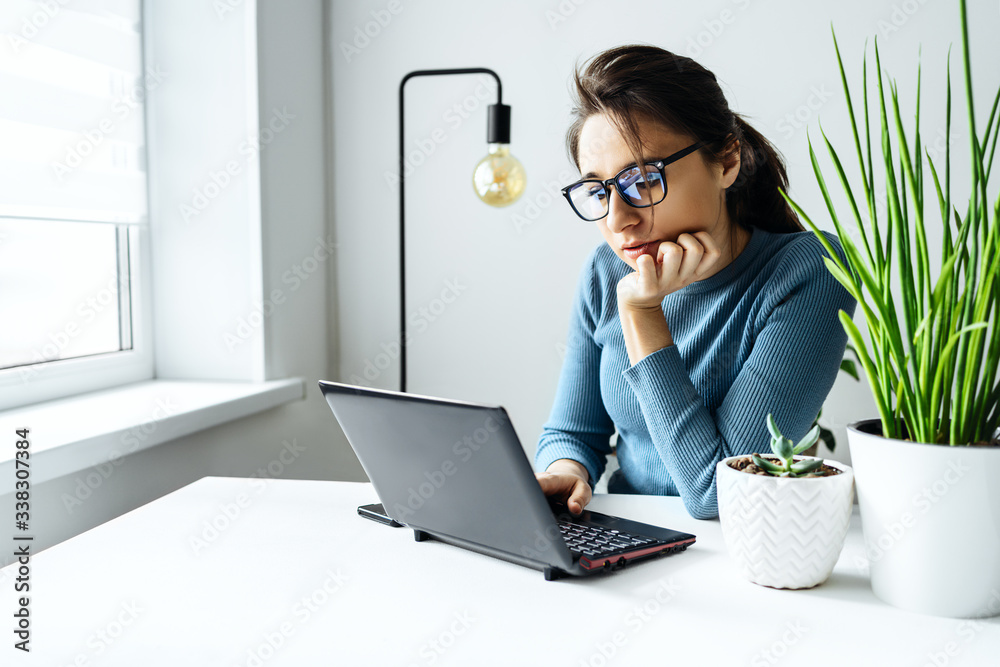 A young woman in glasses works in the home office successful manager or freelancer at work. Distance education. Student woman studying in her room. Online shopping, home work and freelance A young woman in glasses works in the home office successful manager or freelancer at work. Distance education. Student woman studying in her room. Online shopping, home work and freelance