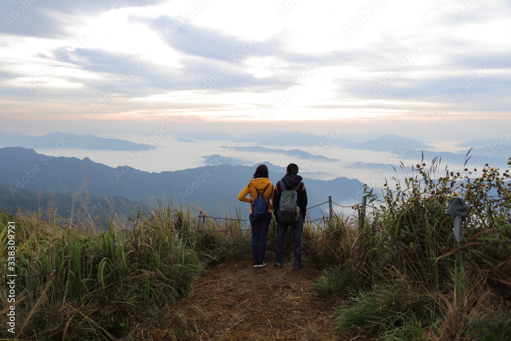 Man and woman standing in the fog and mountain view at Phu Chi Fa National Park, Chiang Rai, Thailand