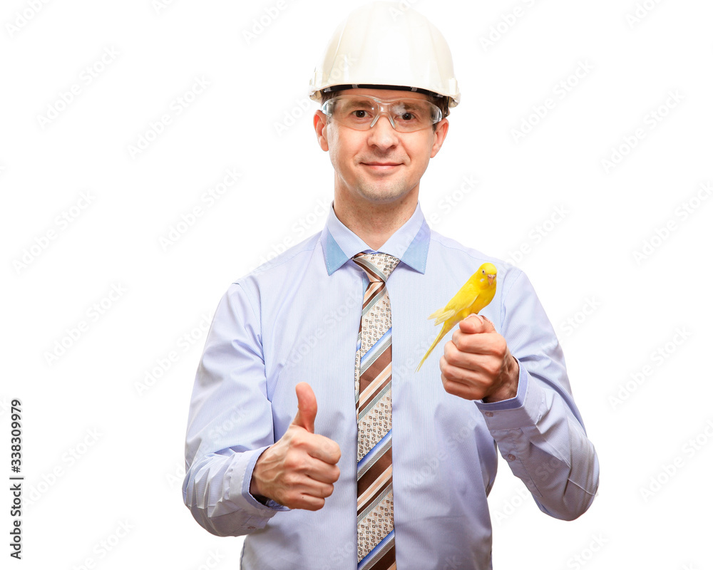 A satisfied male engineer in a white construction helmet, shirt, tie, smiles, holds a bird parrot in his hands, looks into the camera. Isolated A satisfied male engineer in a white construction helmet, shirt, tie, smiles, holds a bird parrot in his hands, looks into the camera. Isolated