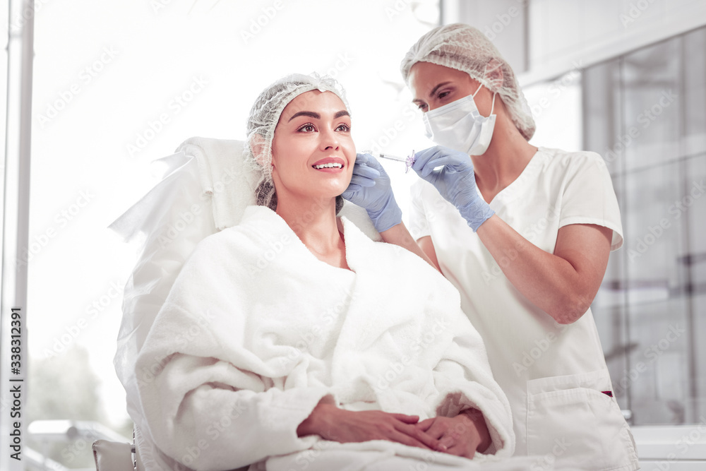 Cosmetologist doing face mesotherapy for her constant client Cosmetologist doing face mesotherapy for her constant client