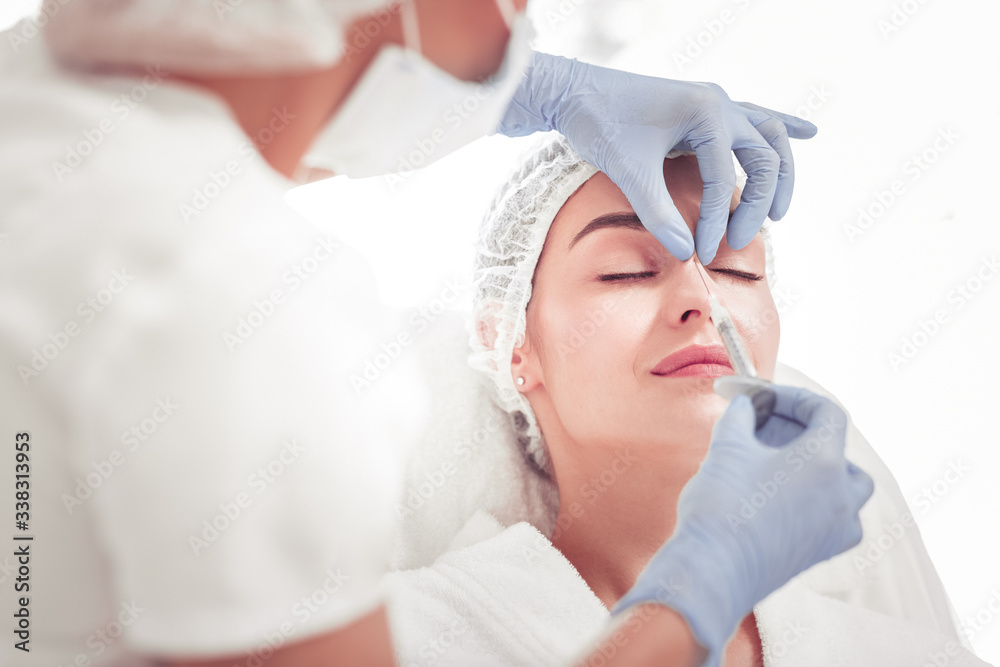 Cosmetologist doing beauty shot into upper part of nose Cosmetologist doing beauty shot into upper part of nose