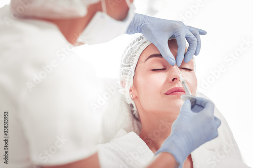 Cosmetologist doing beauty shot into upper part of nose