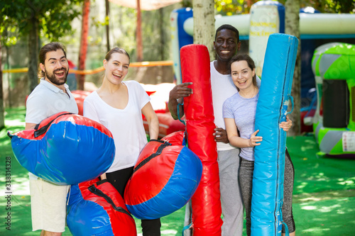 Portrait of happy friends with inflatable logs and pillows at an amusement park