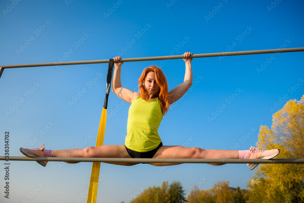 Side view of a beautiful european young woman athlete doing the splits while sitting on a warm summer day. sport active lifestyle concept Side view of a beautiful european young woman athlete doing the splits while sitting on a warm summer day. sport active lifestyle concept