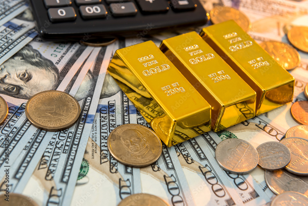 Gold bars with calculator lying on dollar bills background. Save money concept Gold bars with calculator lying on dollar bills background. Save money concept
