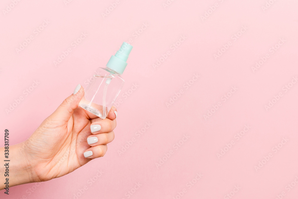 Close up of cosmetics bottle in female hand at pink background with copy space Close up of cosmetics bottle in female hand at pink background with copy space