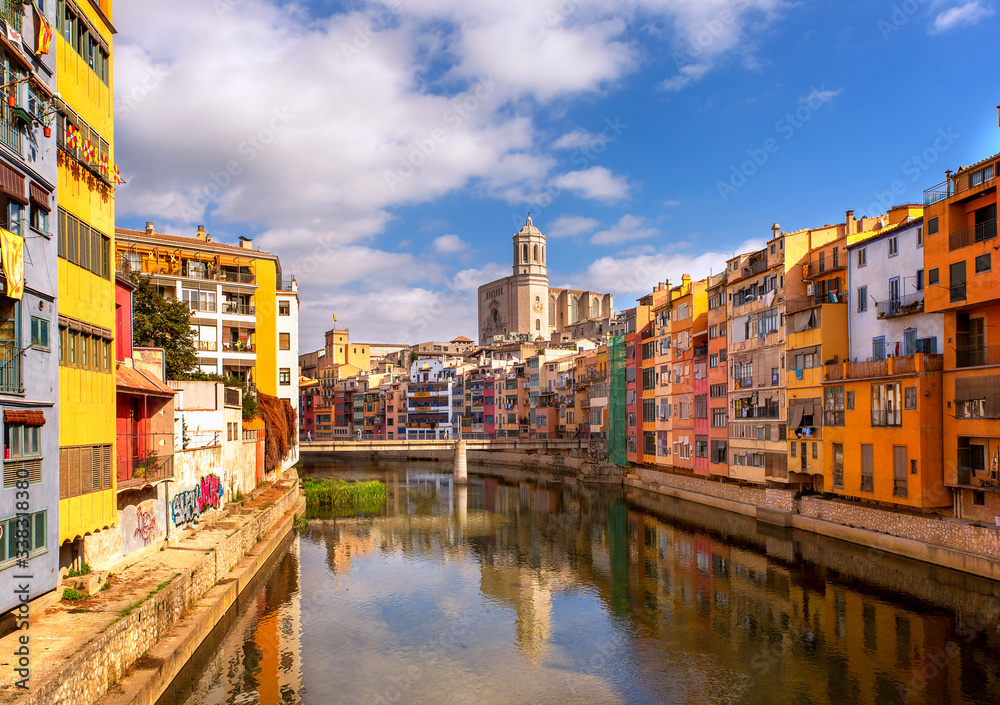 Colorful houses on the Onyar river with reflection in the water on a summer sunny day. The sights of Girona are cities in Catalonia, Spain. City landscape.
