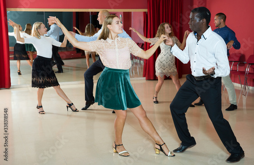 Young people dancing lindy hop in pairs in modern dance hall