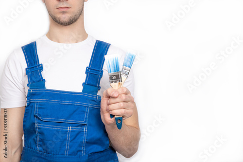 The guy holds brushes in his hands. The guy paints the walls