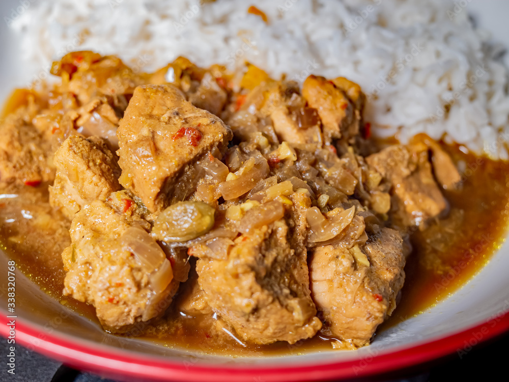 Close up of spicy pork madras curry and white basmati rice in a serving bowl with selective focus on the pork, i.e. the foreground Close up of spicy pork madras curry and white basmati rice in a serving bowl with selective focus on the pork, i.e. the foreground