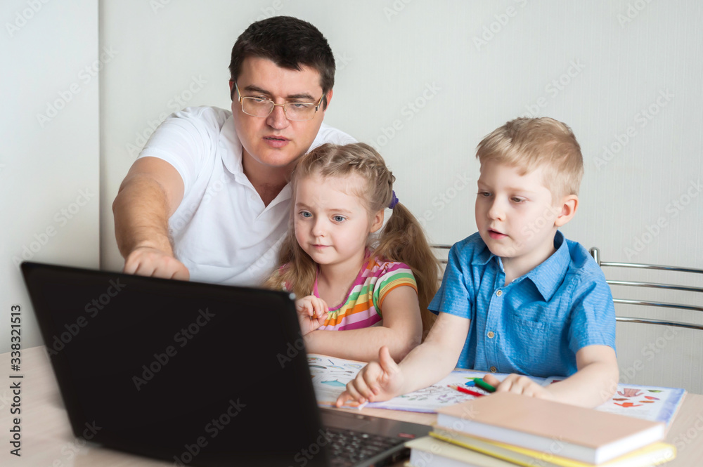 Distance learning online education. Dad explains to the boy and girl the task at home with a digital tablet laptop. Sitting at the table.