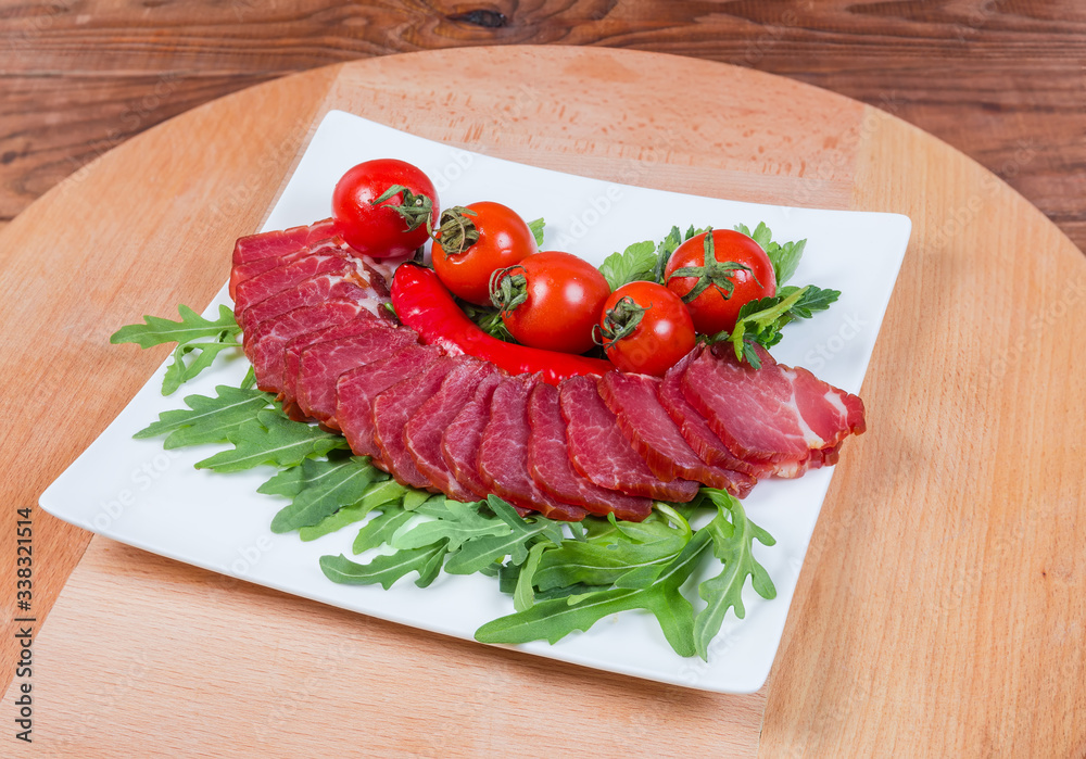 Dried-smoked pork neck, herbs and cherry tomatoes on dish Dried-smoked pork neck, herbs and cherry tomatoes on dish