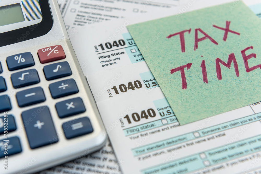 Tax financial forms with pen and calculator and sticker with text Tax Time Tax financial forms with pen and calculator and sticker with text Tax Time