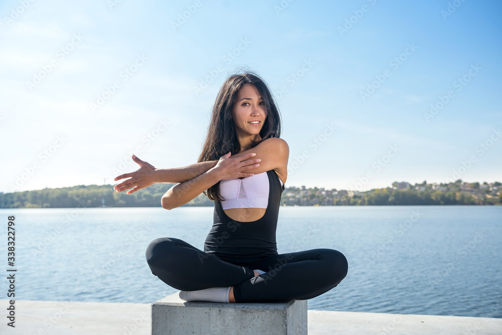 Healthy woman resting and doing  stretching excercise outdoor near the lake