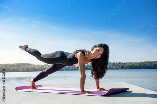 young athletic woman doing push ups. Girl doing fitness exercises near the lake at daytime.