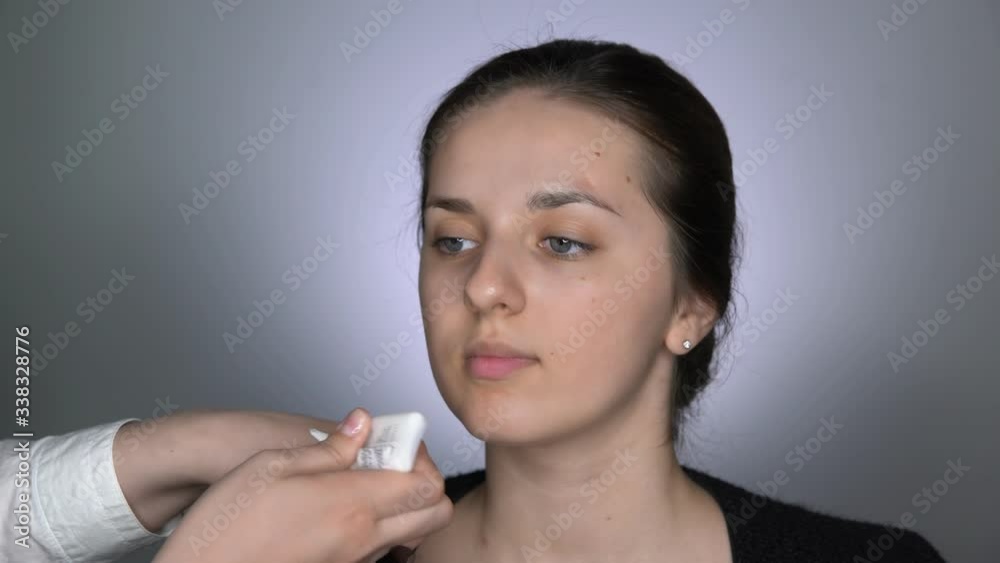 Process of Professional Makeup for beautiful and gorgeous woman sitting at the Studio. Make up Artist applies skin care cream using makeup brush Process of Professional Makeup for beautiful and gorgeous woman sitting at the Studio. Make up Artist applies skin care cream using makeup brush