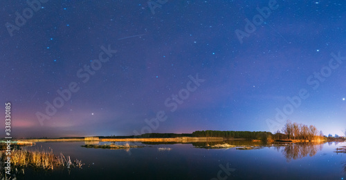 Belarus, Eastern Europe. Night Sky Stars Above Countryside Landscape With River. Natural Starry Sky Above Lake Pond In Early Spring Night. Russian Nature. Panorama, Panoramic View