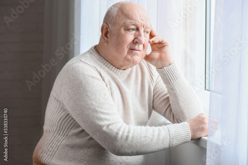 Elderly man suffering from mental disability near window at home © Pixel-Shot