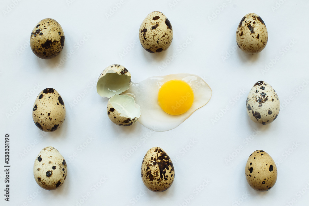 Small quail eggs on white background, one broken, with yellow yolk, eggshell and protein. Easter concept. Unusual paschal photo. Small quail eggs on white background, one broken, with yellow yolk, eggshell and protein. Easter concept. Unusual paschal photo.