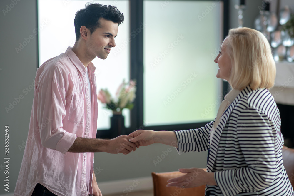 Fototapeta premium Blond psychologist shaking hands her young male patient in her office and smiling