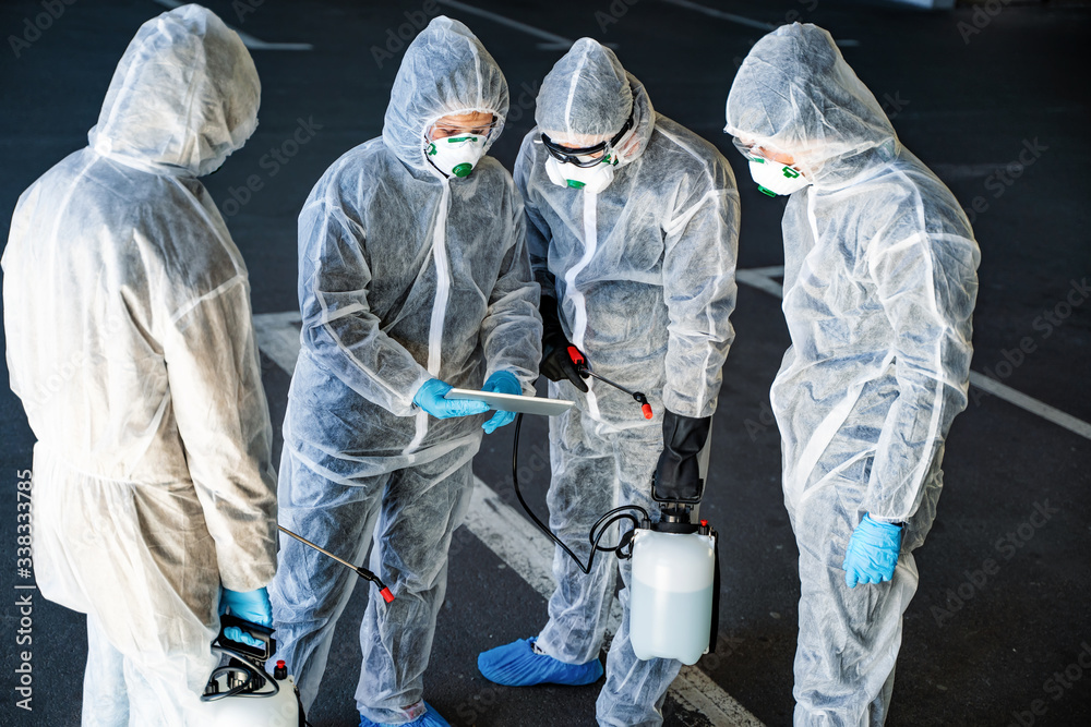 Team of healthcare workers wearing hazmat suits working together to control an outbreak in the city Team of healthcare workers wearing hazmat suits working together to control an outbreak in the city