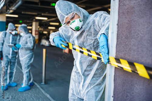 Healthcare worker cordoning off an urban area with barrier tape during an outbreak photo