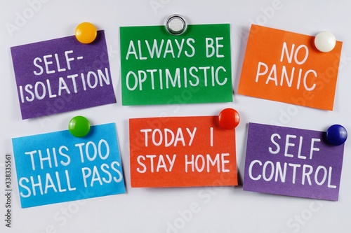 Multi colored stickers with messages "stay at home", "self-isolatuon", "self- control" ,"no panic" and "be optimistic" due quarantine covid-19 are placed on the magnetic white board